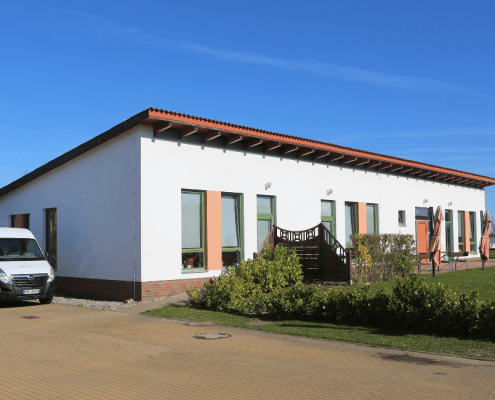 Das Haus der Tagesgruppen der Stralsunder Werkstätten bei Sonnenschein. Daneben steht ein Lieferwagen des Unternehmens.