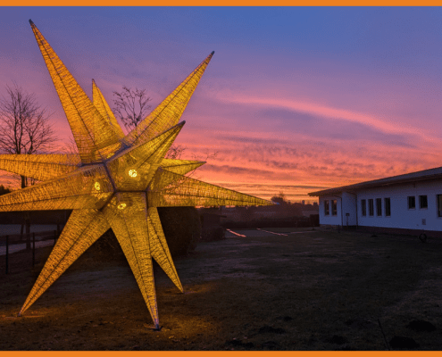 Ein 7 Meter hoher Stern vor der Hauptwerkstatt der Stralsunder Werkstätten leuchtet in orange.